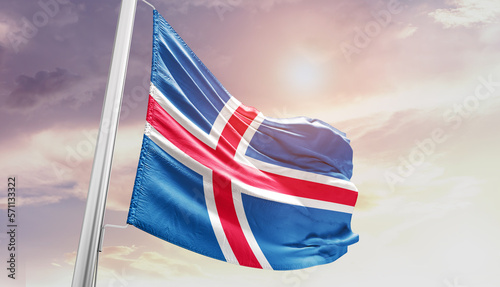 Waving Flag of Iceland in Blue Sky. The symbol of the state on wavy cotton fabric.