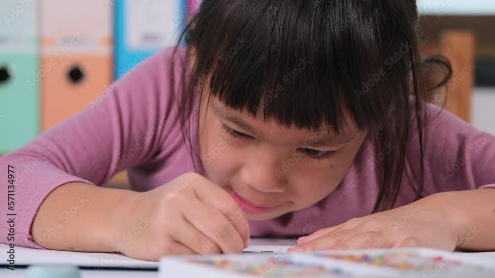 Happy little girl drawing with crayon on paper sitting at table in her room at home. Creativity and development of fine motor skills. Happy little girl drawing with crayon on paper sitting at table in her room at home. Creativity and development of fine motor skills.