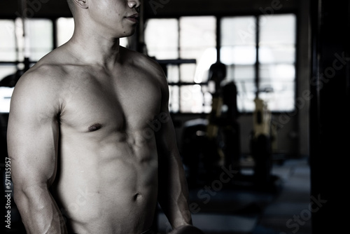 Sexy body of muscular young Asian man in gym. Concept of health care, exercise fitness, Strong muscle mass, body enhancement, fat reduction for men's health supplement product presentation.