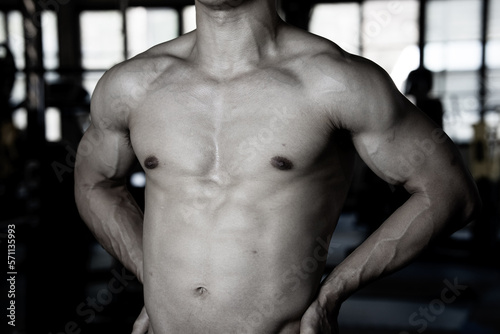 Sexy body of muscular young Asian man in gym. Concept of health care, exercise fitness, Strong muscle mass, body enhancement, fat reduction for men's health supplement product presentation.