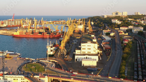 Aerial drone view of sea port with tower cranes and Odessa cityscape. Evening city and sea scape.