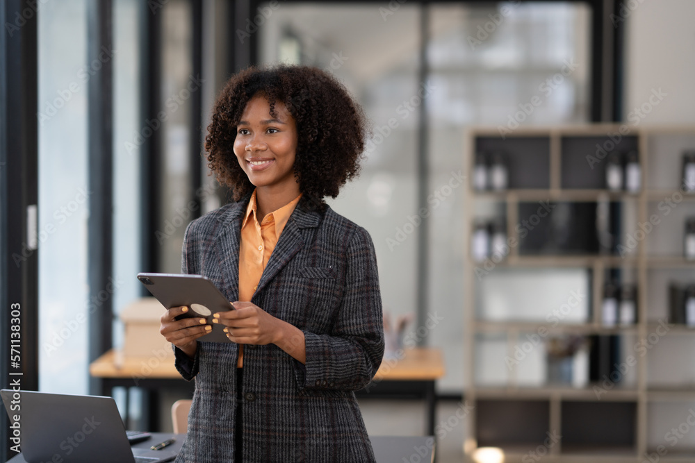 Young smart businesswoman holding digital tablet while standing in the modern office room. Young smart businesswoman holding digital tablet while standing in the modern office room.