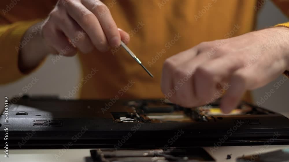 Service center for the repair of digital gadgets. close-up of the hands of the master with a screwdriver unscrew the screws in the laptop. Service center for the repair of digital gadgets. close-up of the hands of the master with a screwdriver unscrew the screws in the laptop.