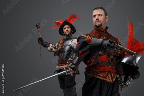 Portrait of isolated on gray background two conquistadors with pistol and torch.