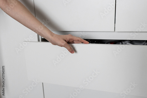 hand pulls out a shelf in a white cabinet