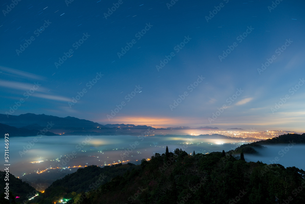 Night view of city lights in the valley. Spectacular cloud waterfall in the sky. The sea of clouds landscape. Dahu Township, Miaoli County, Taiwan
