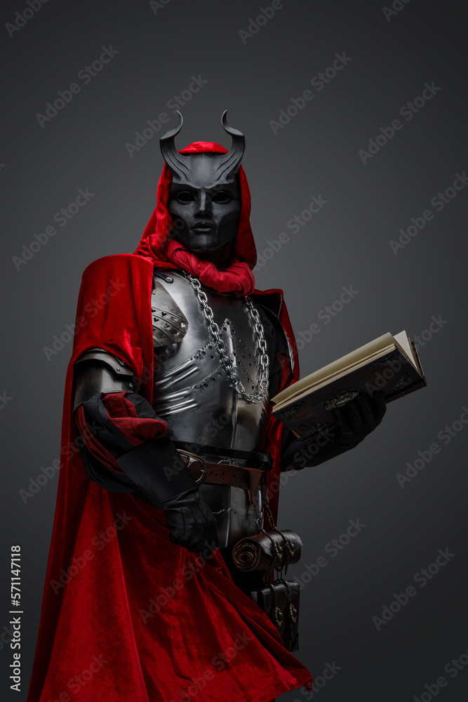 Obraz premium Studio shot of creepy dark cultist dressed in red robe holding book.