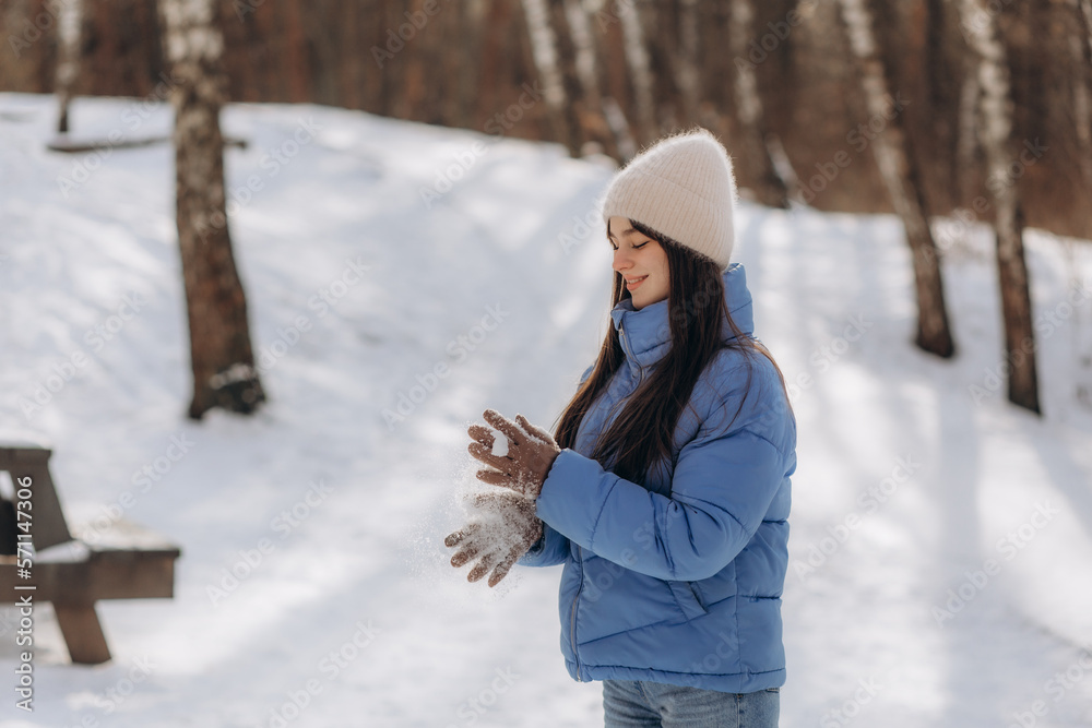 Young beautiful smiling girl holding snow in hands