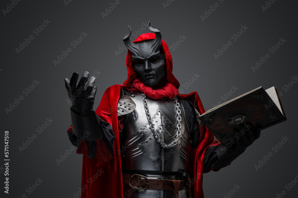 Fototapeta premium Portrait of evil knight with book dressed in red robe and plate armor.