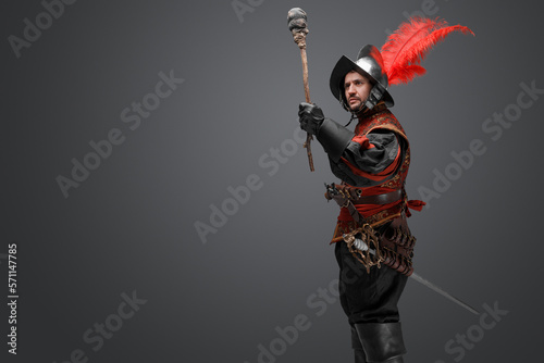 Shot of conquistador explorer dressed in plumed helmet and red attire holding torch.