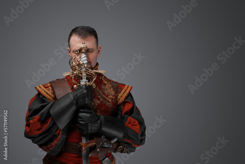 Portrait of mediaeval conquistador dressed in costume holding sword.