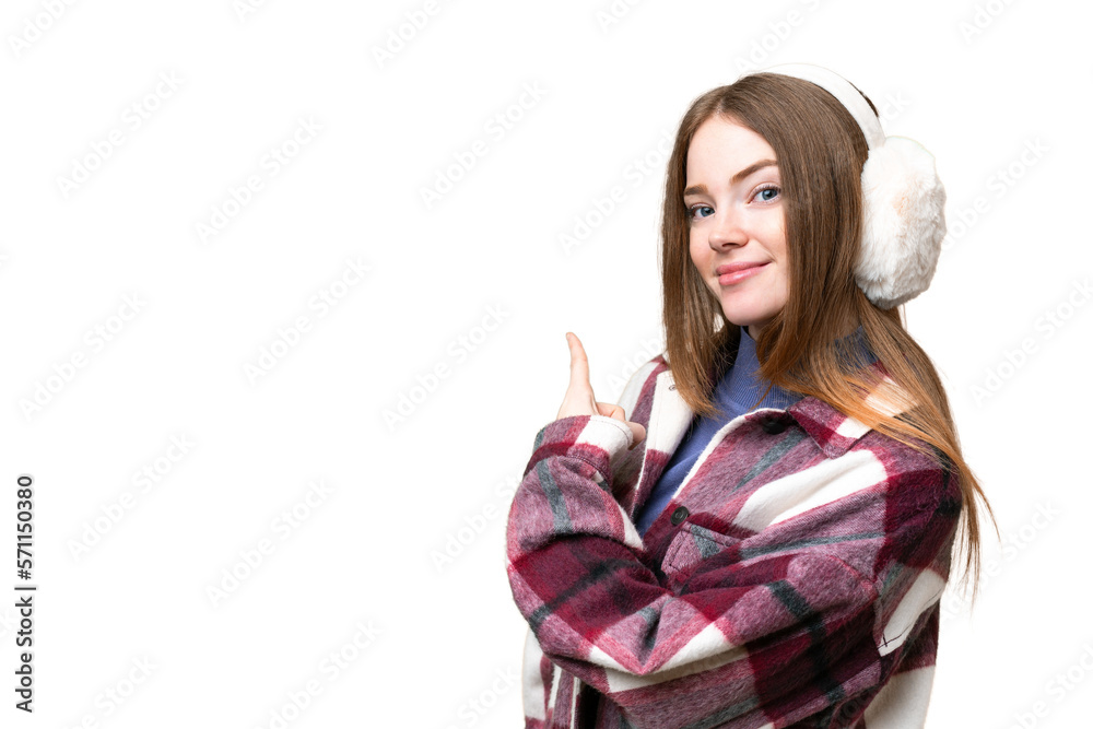 Young pretty woman wearing winter muffs over isolated chroma key background pointing back Young pretty woman wearing winter muffs over isolated chroma key background pointing back