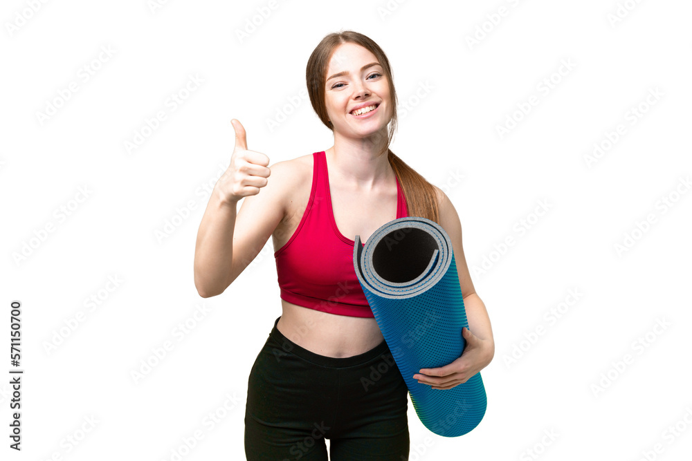 Young sport woman going to yoga classes while holding a mat over isolated chroma key background with thumbs up because something good has happened Young sport woman going to yoga classes while holding a mat over isolated chroma key background with thumbs up because something good has happened