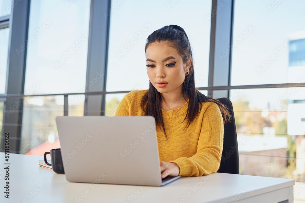 Young businesswoman working on laptop at desk in office Young businesswoman working on laptop at desk in office