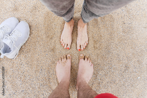 Man and woman standing barefeet on sand at beach photo