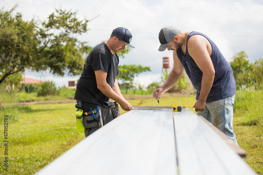 Two men preparing steel excursion for solar panel installation. Two men preparing steel excursion for solar panel installation.