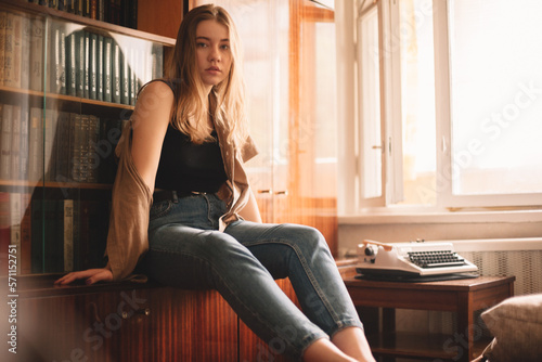 Young woman sitting by bookshelf photo
