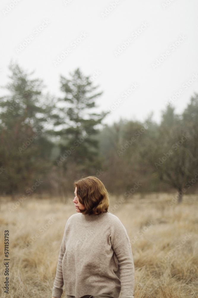 Woman standing by forest in foggy weather Woman standing by forest in foggy weather