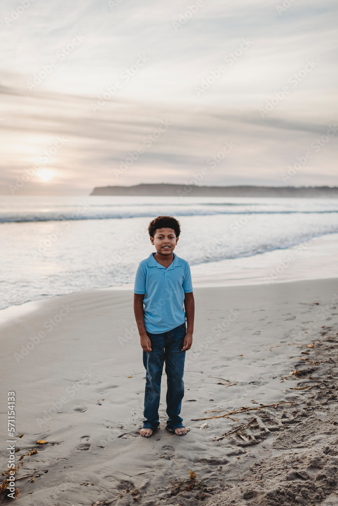 Portrait of young school-aged boy smiling at beach during sunset Portrait of young school-aged boy smiling at beach during sunset