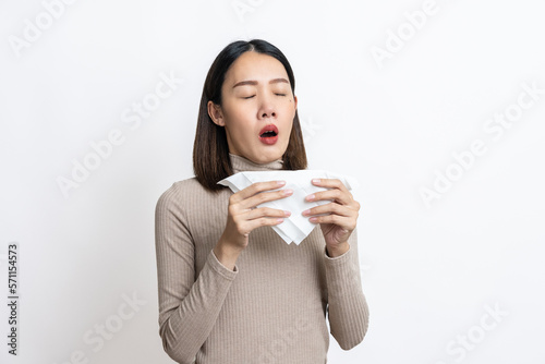 Portrait of beautiful young asian sick woman over isolated white background being wrapped in scarf sneezing  suffering from runny nose and high temperature. Cold and fever concept.