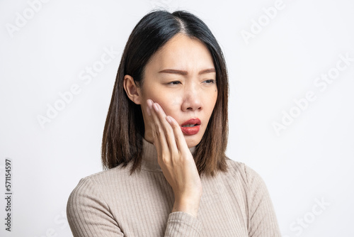 Portrait of beautiful young asian sick woman over isolated white background pressing sore cheek, suffering acute toothache, periodontal disease, cavities or jaw pain. Dental problems concept.