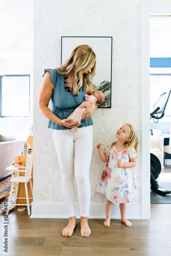 Portrait of a mother laughing with her toddler while holding her baby Portrait of a mother laughing with her toddler while holding her baby