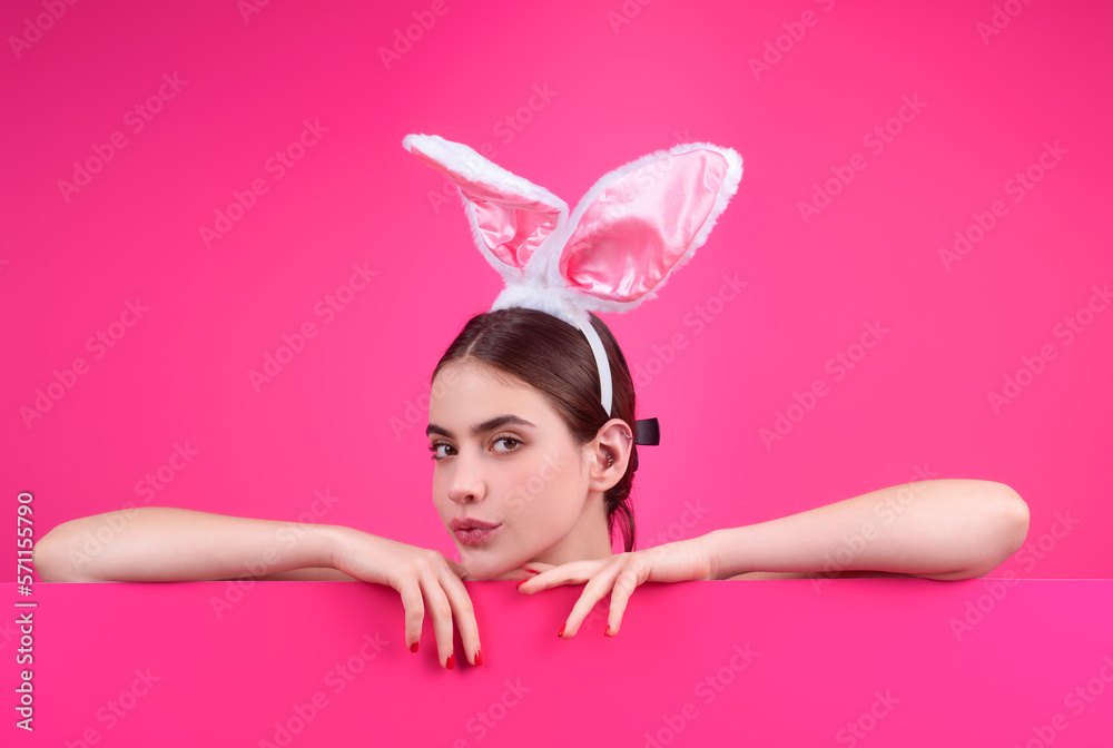 Easter girl. Young woman wearing Easter bunny ears holding decorative colored eggs on studio background with copy space.