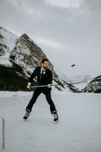 hockey player with suit on juggles puck on frozen lake in mountains
