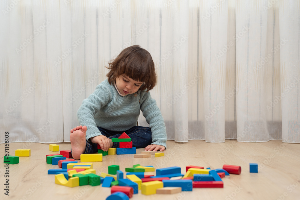 Female toddler building a tower with toy blocks on floor. Female toddler building a tower with toy blocks on floor.