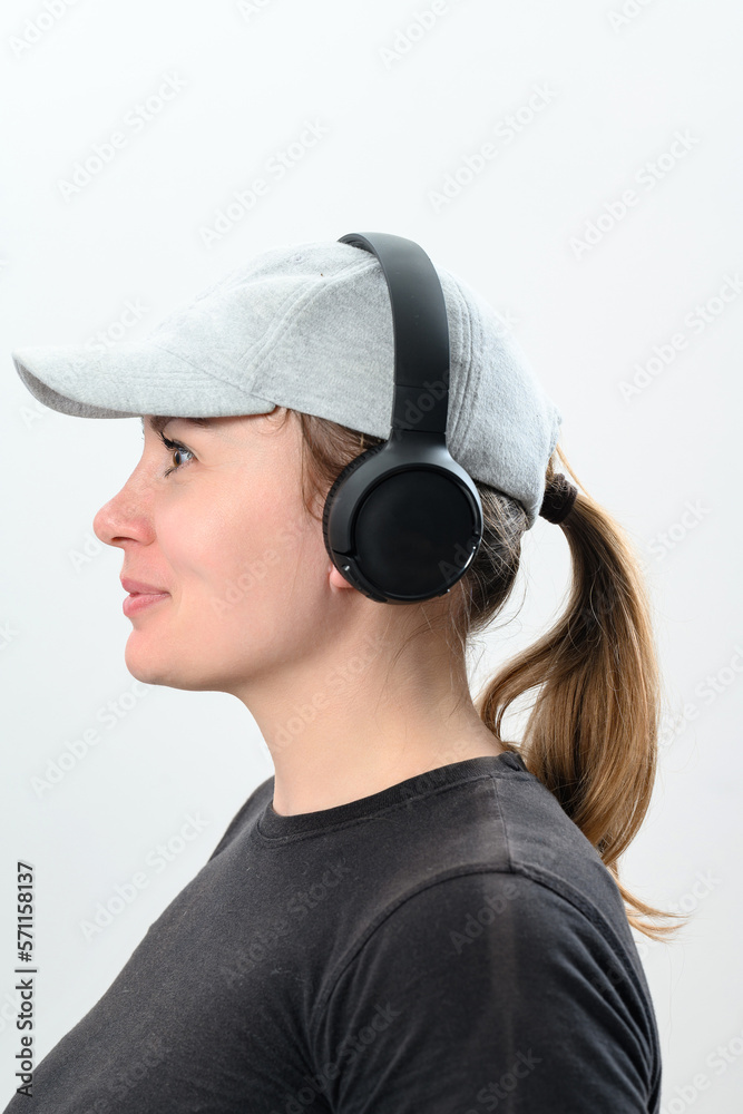Portrait of a girl on a white background with wireless headphones and a hat on her head. Portrait of a girl on a white background with wireless headphones and a hat on her head.