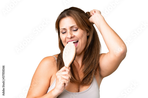 Middle age woman over isolated background with hair comb and singing