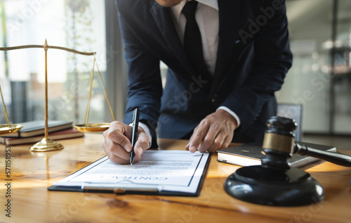 Young Asian lawyer or legal advisor reading clarification on business agreement with the signing of the investment contract according to the laws and regulations in the office.