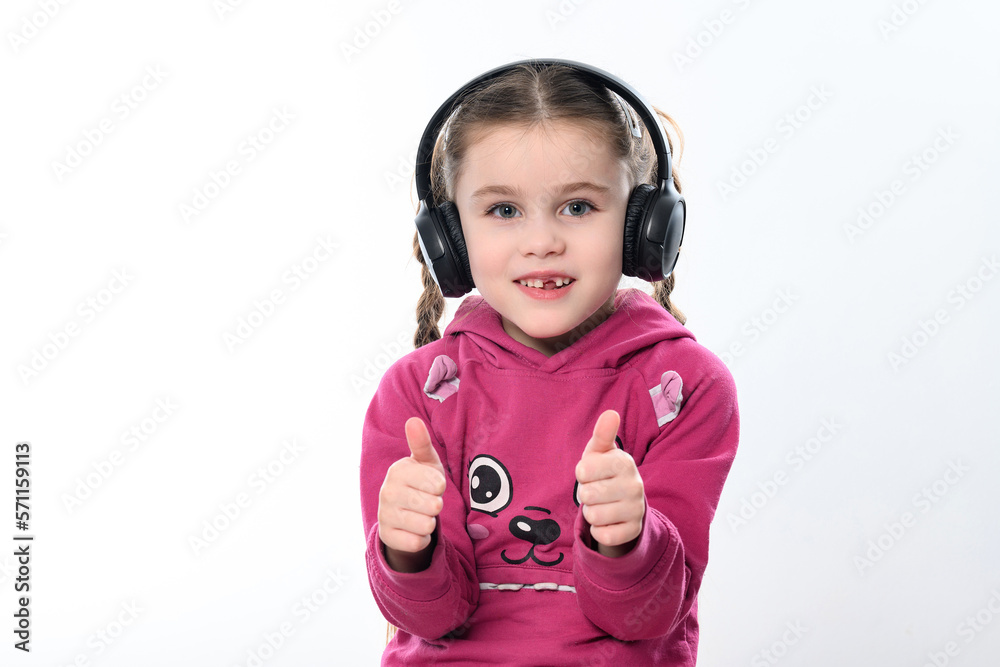 A child with headphones on a white background, a cheerful and beautiful girl with headphones. A child with headphones on a white background, a cheerful and beautiful girl with headphones.