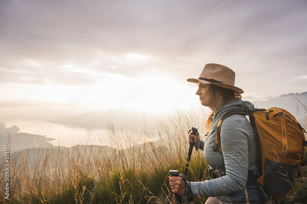 Woman with backpack and hiking poles standing under sky Woman with backpack and hiking poles standing under sky
