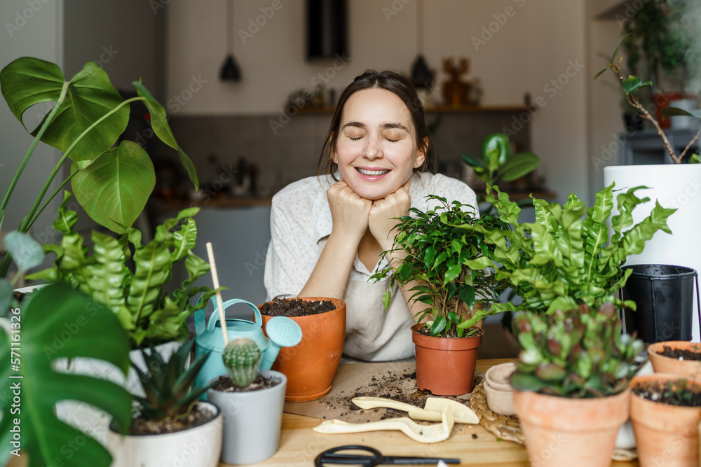Smiling woman with eyes closed leaning on table by plants at home Smiling woman with eyes closed leaning on table by plants at home