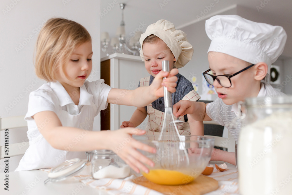 Girl with brothers mixing eggs in bowl at kitchen Girl with brothers mixing eggs in bowl at kitchen