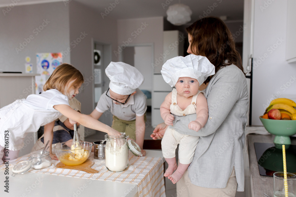 Mother carrying boy with children preparing dough in kitchen Mother carrying boy with children preparing dough in kitchen