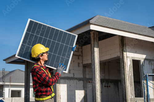 Engineers in helmets installing solar panel system outdoors. technician use a the Electric drill installing the solar panels at roof top of home and home office.
