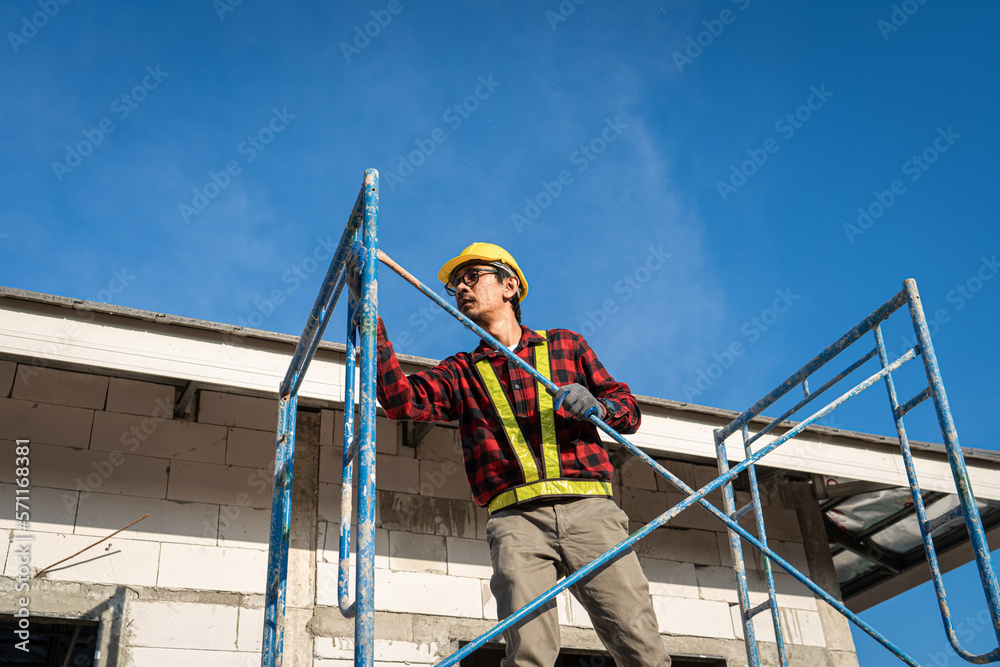 Naklejka premium Construction worker wearing safety harness and safety line working on scaffolding at new house under construction.