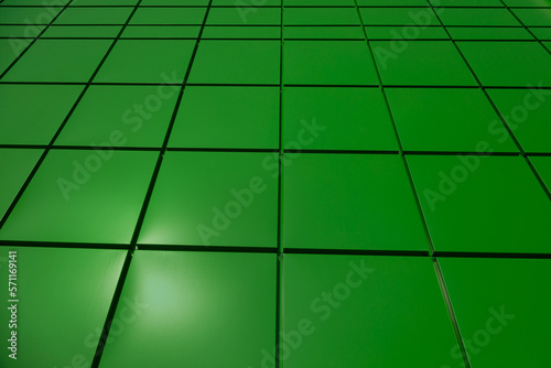 a fragment of a green aluminum ventilated facade with a gutter on a blue sky background