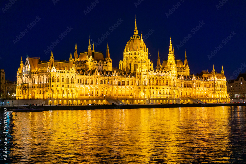 The Budapest Parliament building at night, with the Danube in the foreground