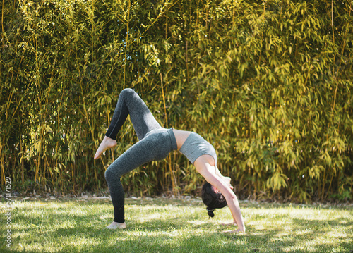 young girl doing yoga in the garden with mat