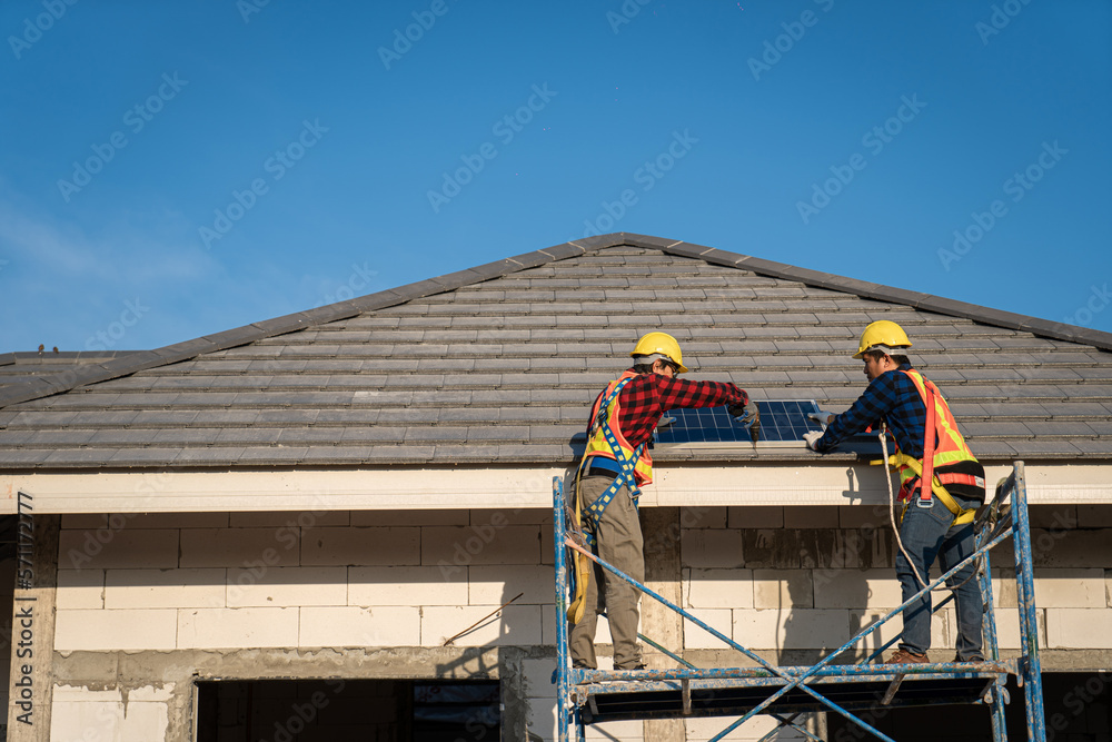 Engineers in helmets installing solar panel system outdoors. technician use a the Electric drill installing the solar panels at roof top of home and home office. Engineers in helmets installing solar panel system outdoors. technician use a the Electric drill installing the solar panels at roof top of home and home office.