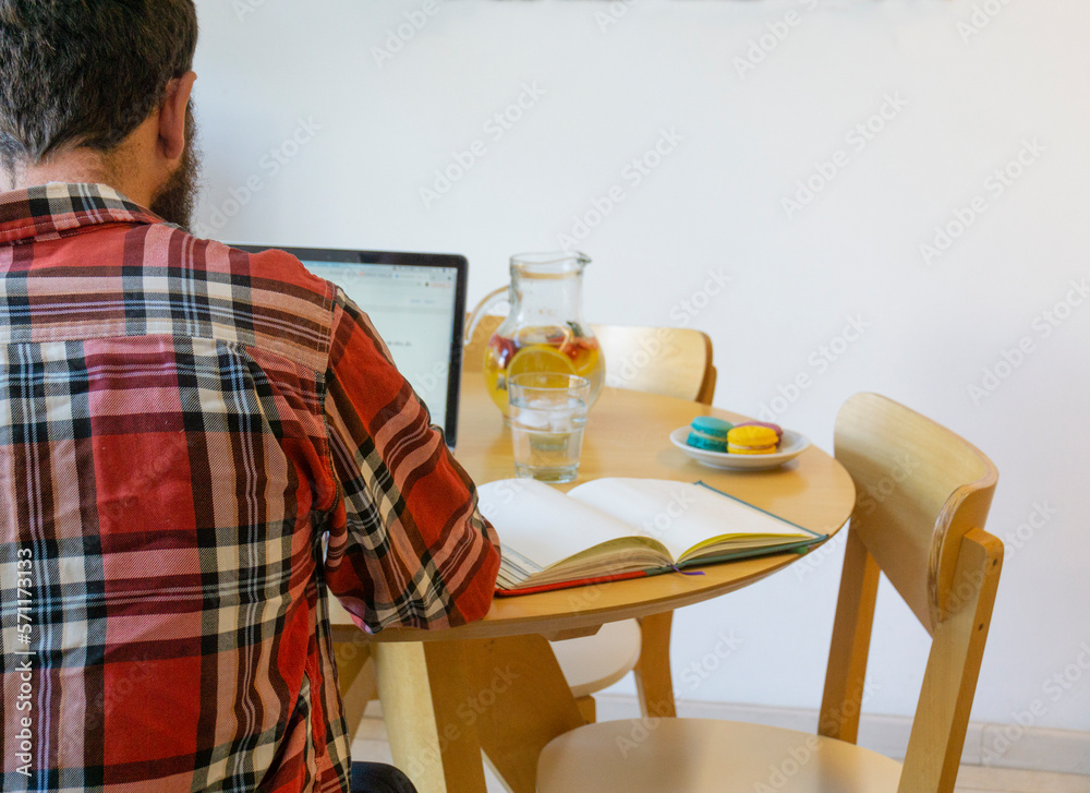 Rear view of man working on his laptop in the table with food Rear view of man working on his laptop in the table with food