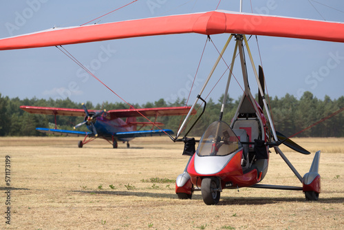  RECREATIONAL AVIATION - Powered hang glider and airplane at a field airport
