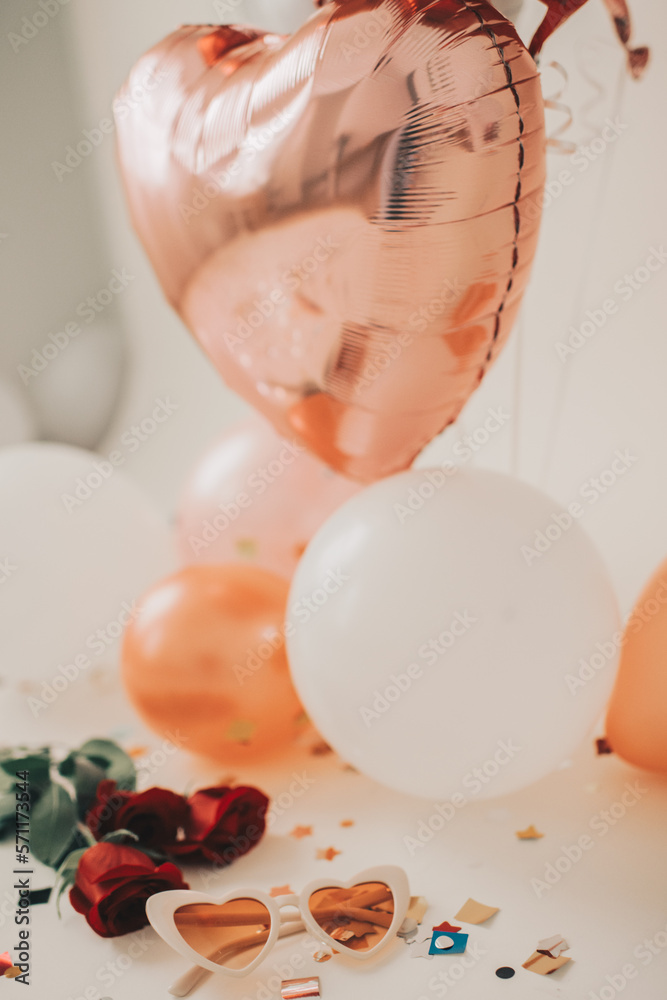 Heart sunglasses next to confetti, roses and balloons for holiday Heart sunglasses next to confetti, roses and balloons for holiday