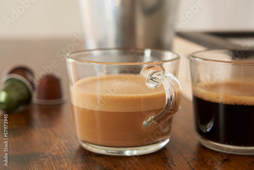 Cups of latte and black coffee with espresso capsules