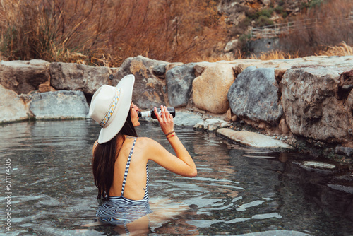 portrait of woman in hat drinking beer in natural hot springs photo