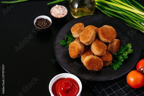 fried chicken nuggets on a black plate, ketchup in a saucepan, v