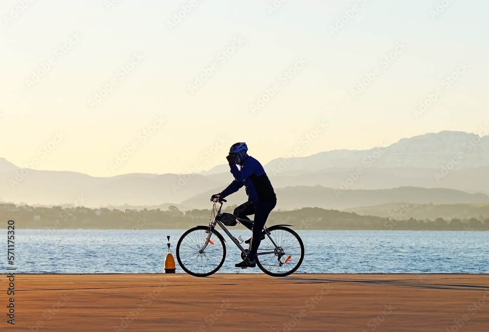 Fototapeta premium Silhouette of a cyclist near the seashore